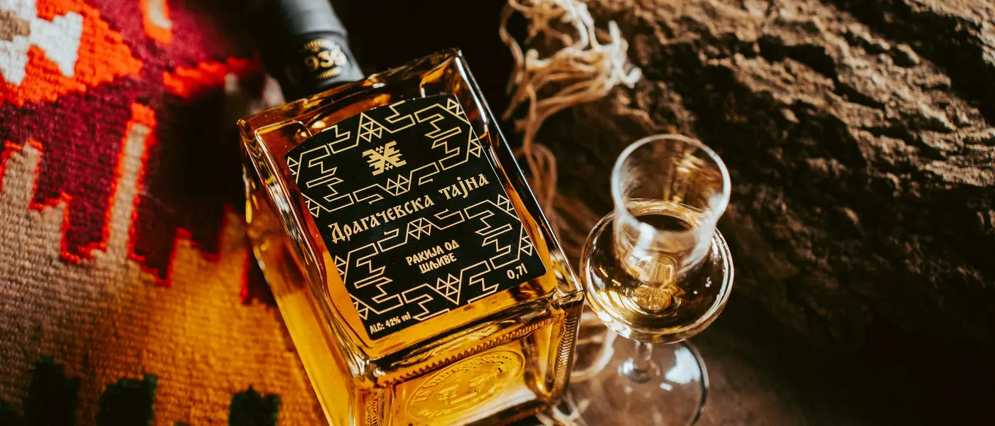 Bottle of aged plum rakija beside a tasting glass — distillery and winery website design
